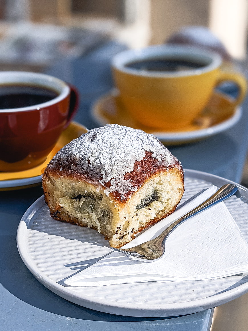 Poppy seed sourdough bun with coffee cups on blue table
