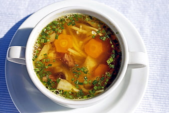 Overhead view of hearty vegetable and meat soup in white bowl
