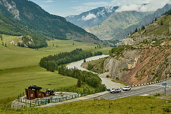 Scenic mountain valley with winding river and roadside memorial