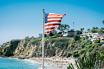 American Flag Waving Over Crowded Beach and Cliffs