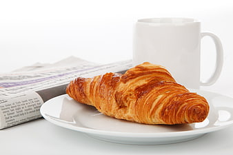 Golden Croissant on White Plate with Coffee Mug and Newspaper