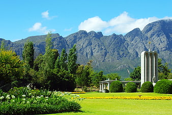 Landscape of manicured gardens with mountains and monument