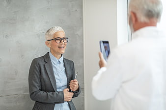 Senior woman smiling while man takes photo with smartphone