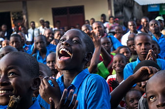 Joyful African Boy Singing In School Uniform Amidst Crowd