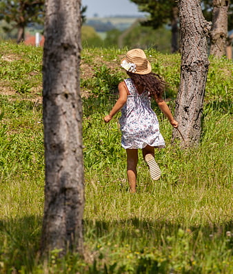Little girl running through grassy field in summer dress
