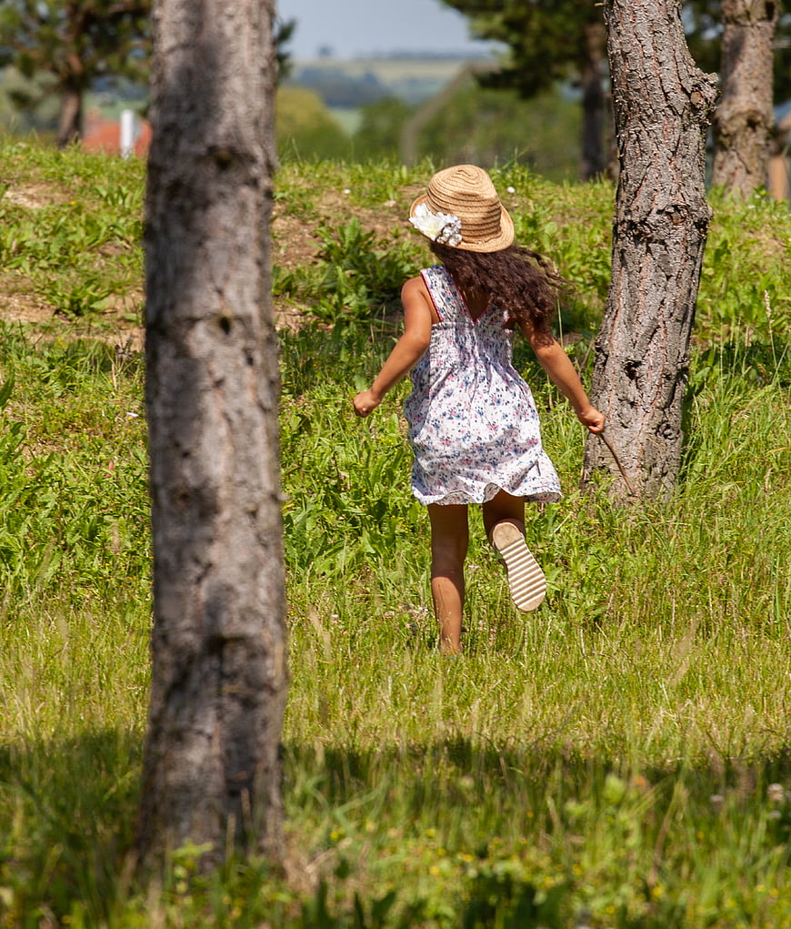 Little girl running through grassy field in summer dress