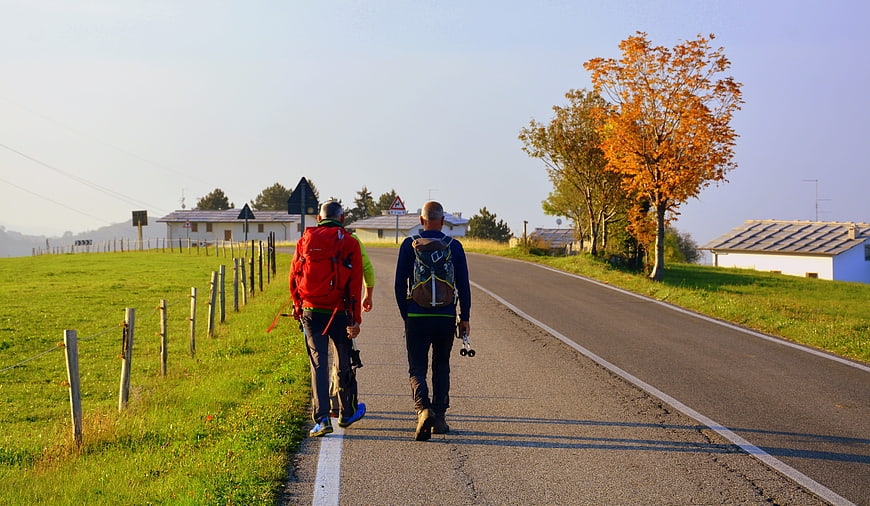 Hikers walking on country road in autumn landscape