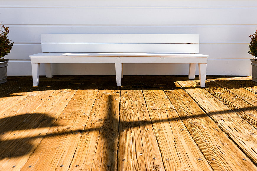 White Wooden Bench on Sunlit Deck with Shadows
