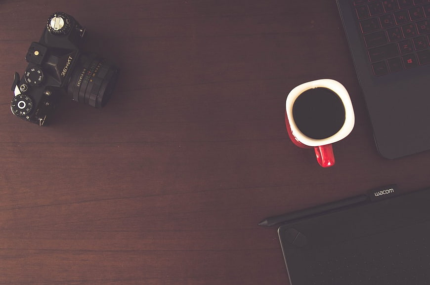 Flat Lay of DSLR Camera, Coffee, and Laptop on Wooden Desk