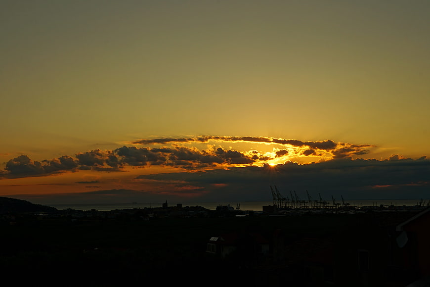 Dramatic sunset over industrial port with cranes and clouds