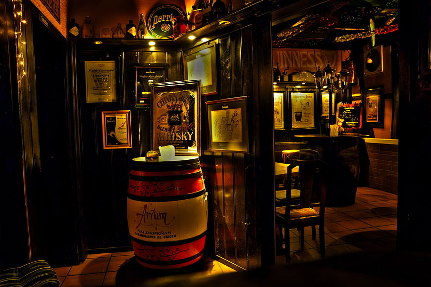 Dimly lit Irish pub interior with whiskey barrel and vintage decor