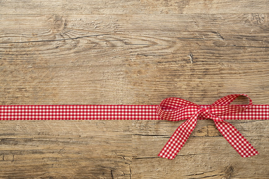 Red gingham ribbon bow on rustic wooden background