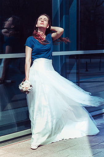 Woman in white skirt and blue top holding bouquet