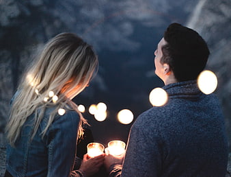 Couple holding candles with bokeh lights at night