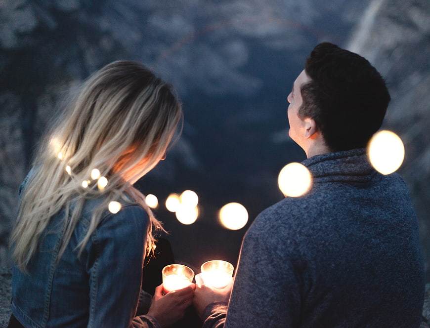 Couple holding candles with bokeh lights at night
