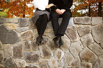 Couple Sitting On Stone Wall In Autumn Park
