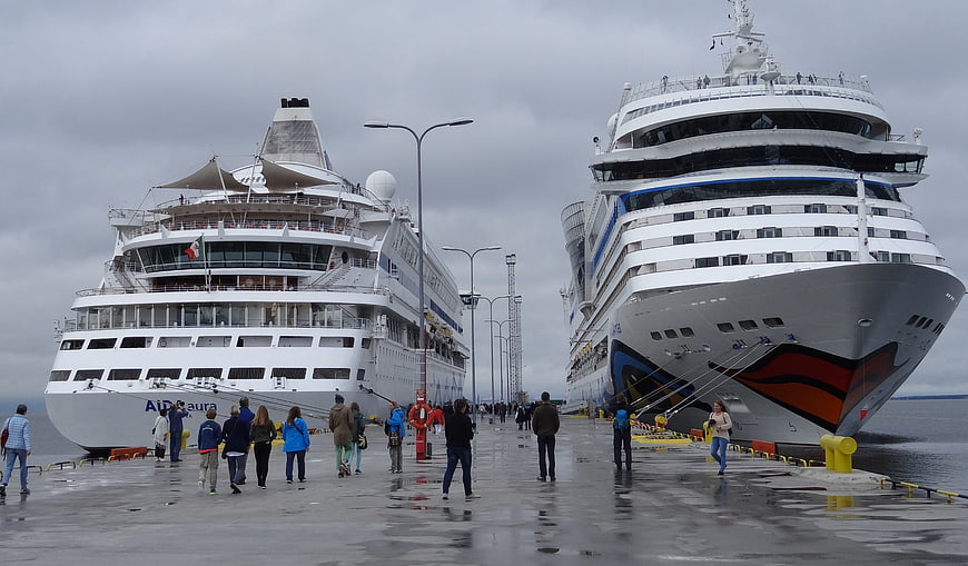 Two large cruise ships docked at a wet pier with passengers