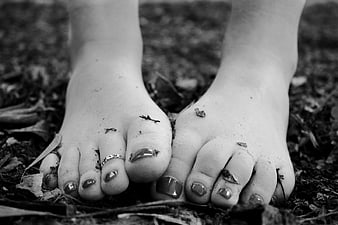 Close-up of bare feet with painted toenails on forest floor