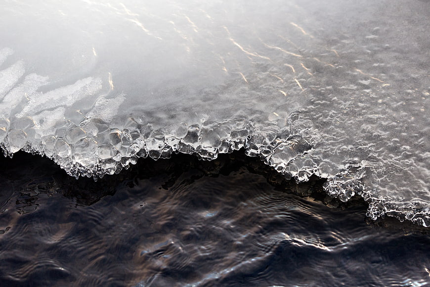 Close-up of melting ice edge on dark flowing water