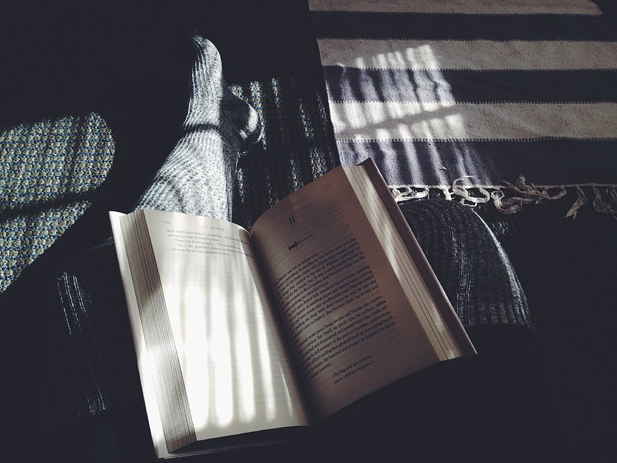 Open book with striped shadows on cozy knitted blanket