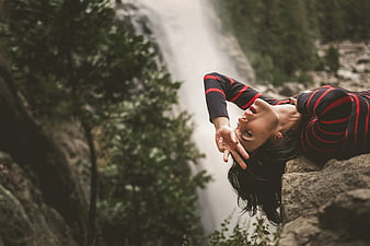 Woman relaxing on rocks near waterfall in nature