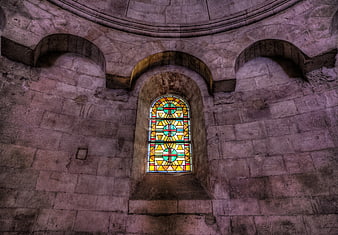 Stained glass window in ancient stone church interior