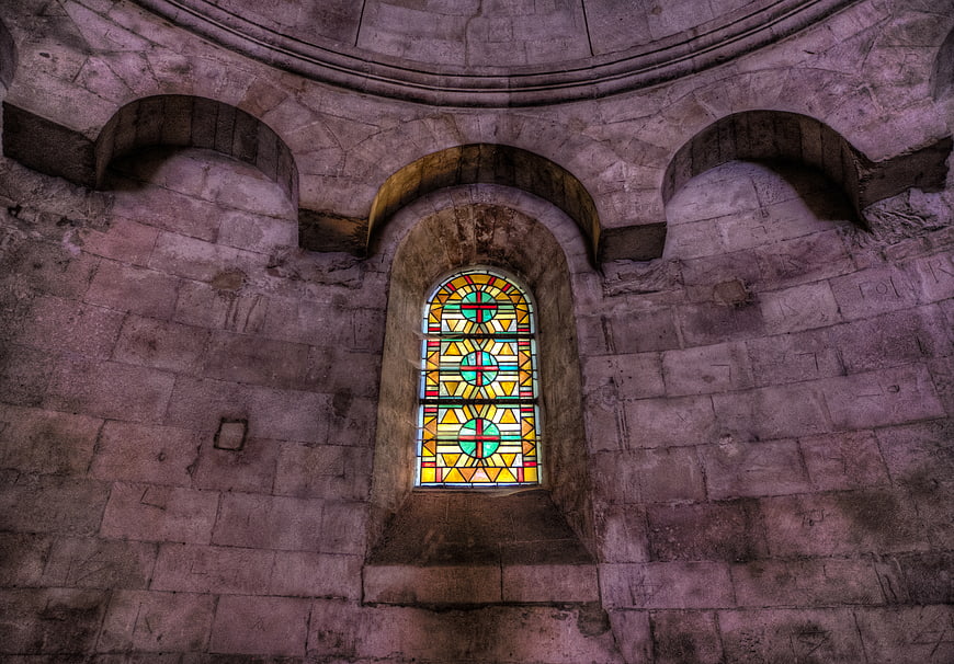 Stained glass window in ancient stone church interior
