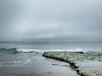 Mossy rocks on a gray stormy ocean coastline