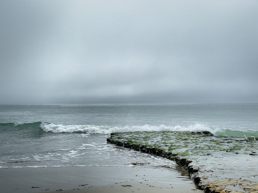 Mossy rocks on a gray stormy ocean coastline