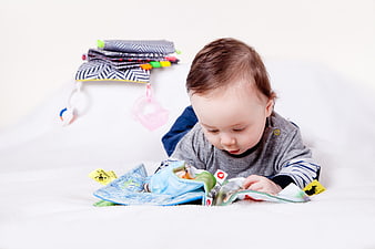 Baby boy exploring colorful cloth book on white background