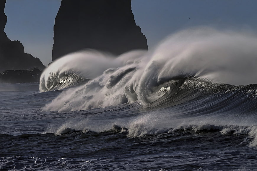 Powerful Ocean Waves Crashing Against Dark Sea Stacks