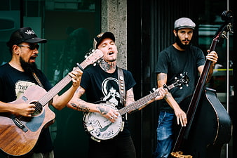 Three male musicians playing acoustic instruments on the street