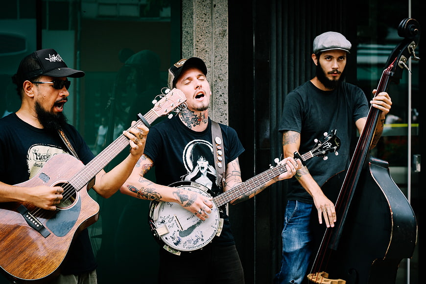 Three male musicians playing acoustic instruments on the street