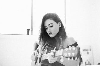 Woman playing acoustic guitar in black and white