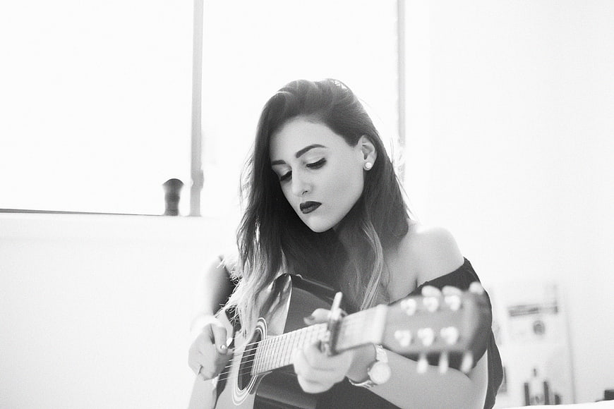 Woman playing acoustic guitar in black and white