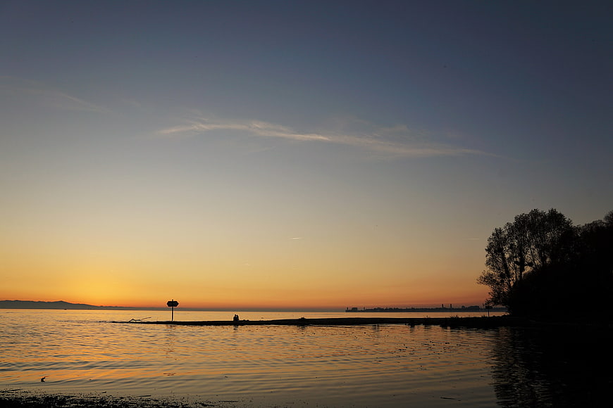 Serene Sunset Silhouette Over Calm Lake Water