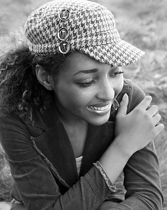 Black and white portrait of smiling woman in houndstooth cap