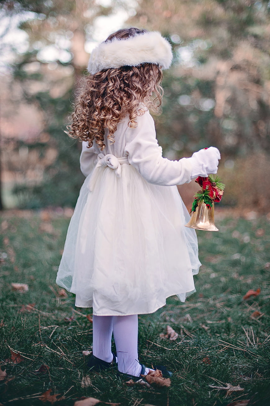 Little Girl in White Dress Holding Christmas Bell