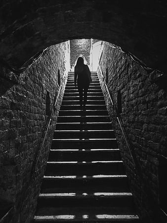 Silhouette of woman walking up dark stone stairs