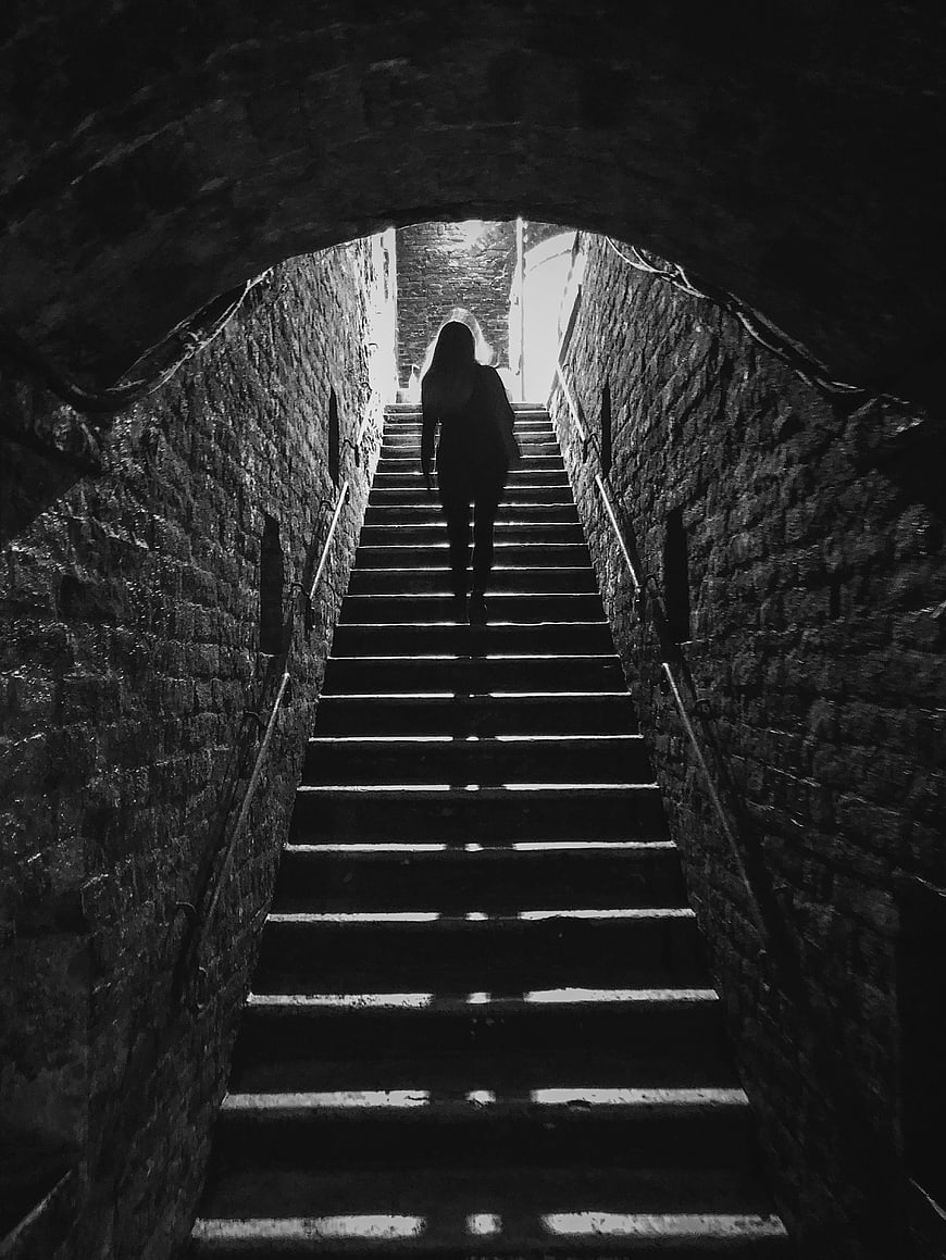 Silhouette of woman walking up dark stone stairs