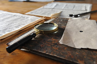 Vintage Magnifying Glass On Old Book And Antique Desk