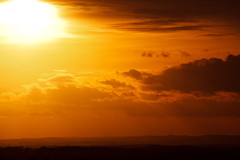 Vibrant Orange Sunset Sky with Dramatic Clouds and Silhouette Horizon