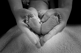Black and white photo of mother holding newborn baby feet