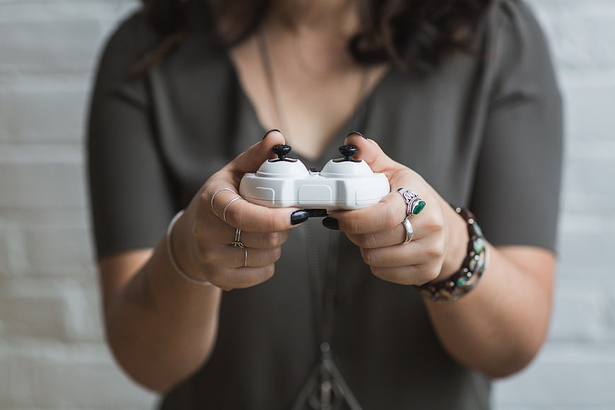 Woman holding white drone controller with black nails