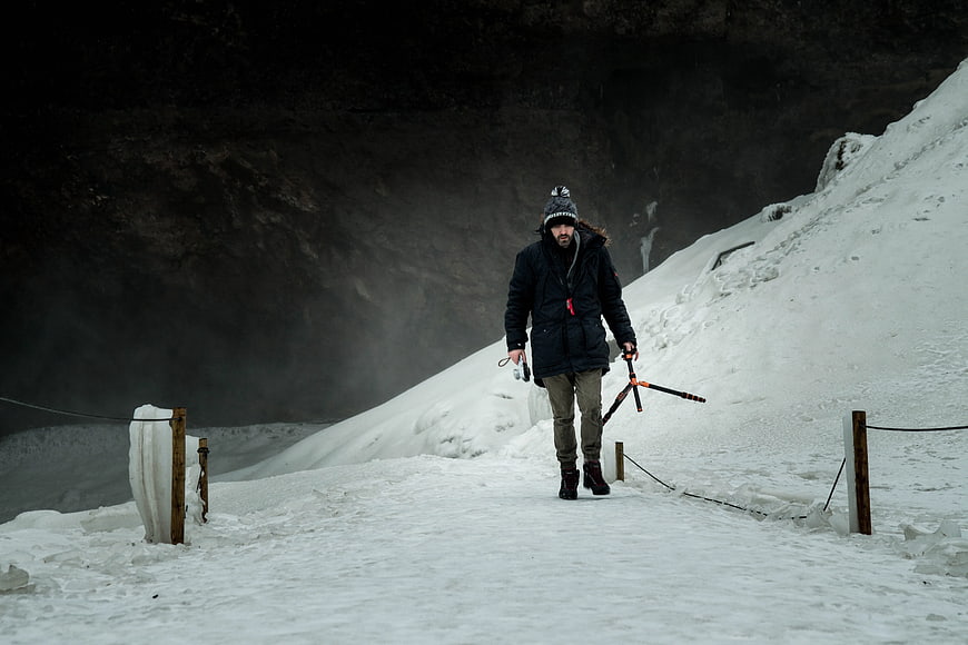 Man Walking on Snowy Path with Camera Gear