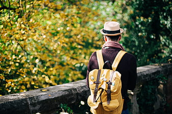Man with Yellow Backpack and Hat in Autumn Park