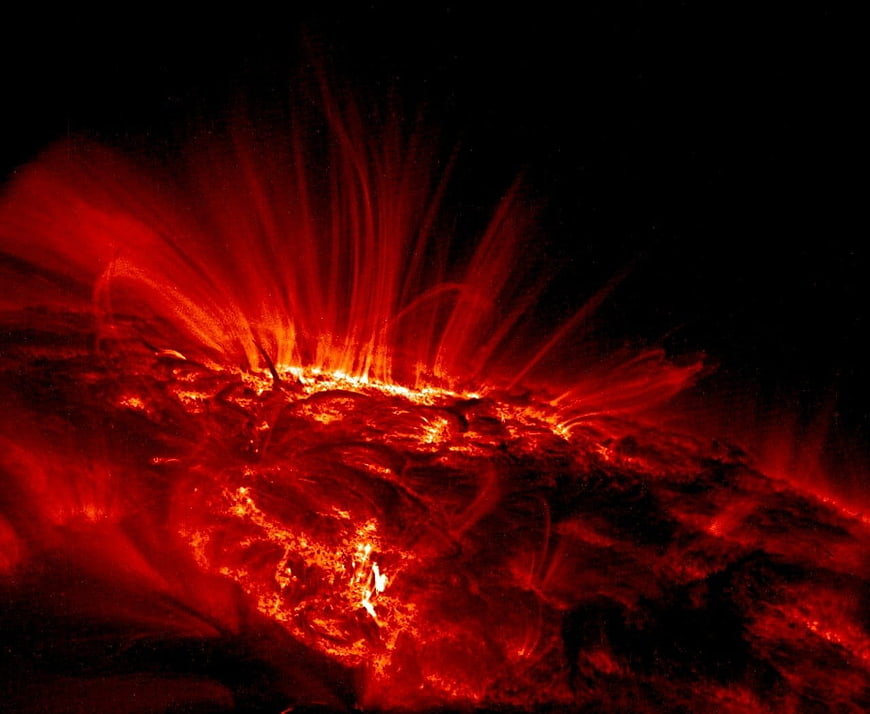 Solar flare eruption with red plasma loops against black space