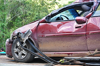 Damaged red car on flatbed tow truck after accident