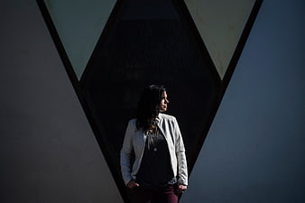 Woman in White Jacket Standing in Geometric Shadow