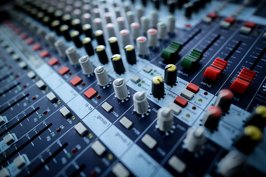 Close-up of professional audio mixing console with faders and knobs